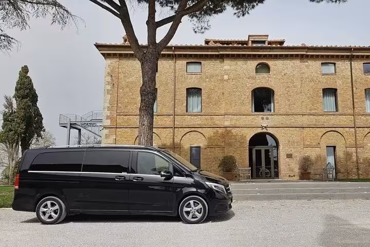 Elegant black van parked in front of a rustic building, ideal for full-day tours and comfortable group travel.
