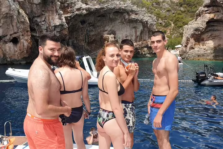 Tour guests on boat near rocky cove, swim stop on Blue Cave & 5 Islands tour to Vis and Hvar from Split