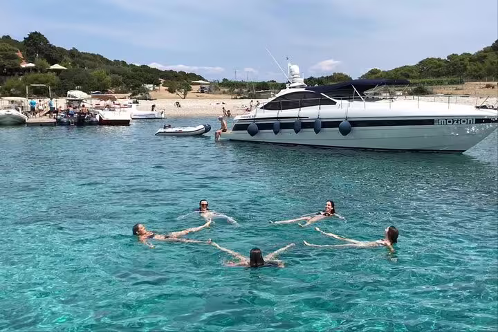 Guests swimming in crystal-clear Adriatic bay beside speedboat on Blue Cave & 5 Islands tour from Split