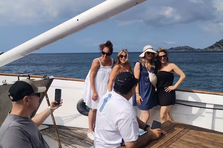 Friends pose for photos on deck during a Blue Coast boat tour, cruising to scenic coves and calanques