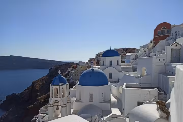 Blue-domed churches of Oia overlooking the Santorini caldera, must-see landmark on highlights sightseeing tour