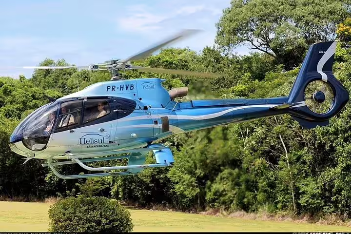 Close-up of a blue helicopter flying near lush greenery in Foz de Iguaçu, offering an exciting panoramic tour experience.