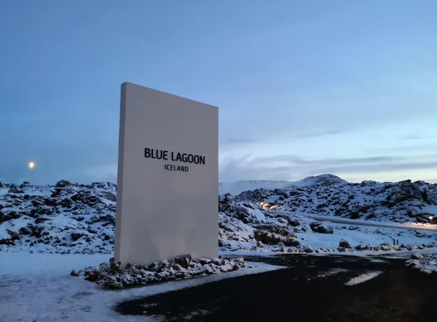 Blue Lagoon Iceland entrance sign surrounded by snow-covered lava fields at dusk