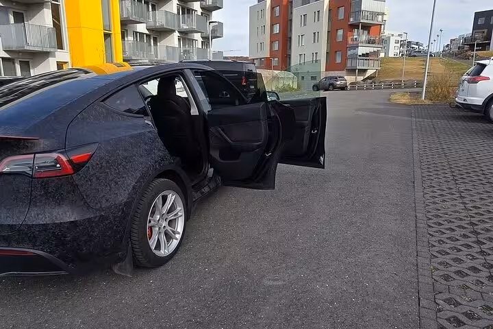 Modern black car with open doors in a Reykjavik lot, perfect for private transfer to Blue Lagoon from Keflavik.