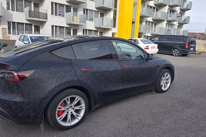 Black car parked in urban setting, highlighting comfortable transfer options for Blue Lagoon tours in Iceland.