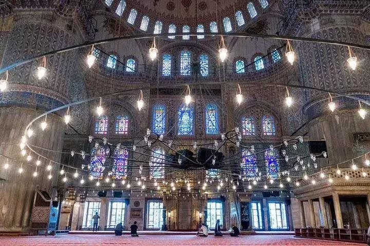 Interior of the Blue Mosque in Istanbul showcasing intricate Ottoman architecture and vibrant stained glass windows.