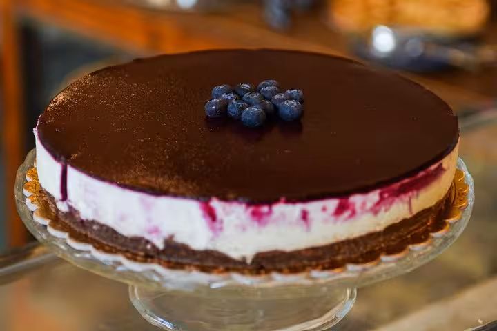 Decadent blueberry-topped cheesecake with a rich chocolate glaze, featured in Rome's Michelin culinary tour.