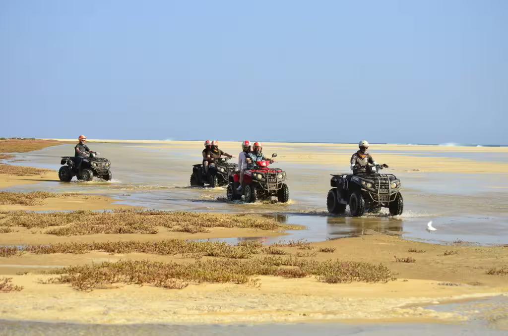 Quad riders traverse sandy terrain on Boa Vista Island's scenic 4-hour tour to Santa Monica beach.