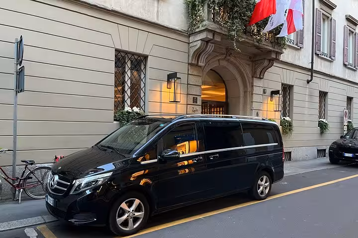 Elegant black Mercedes van ready for Bologna airport to Ravenna cruise terminal transfer outside historic building.