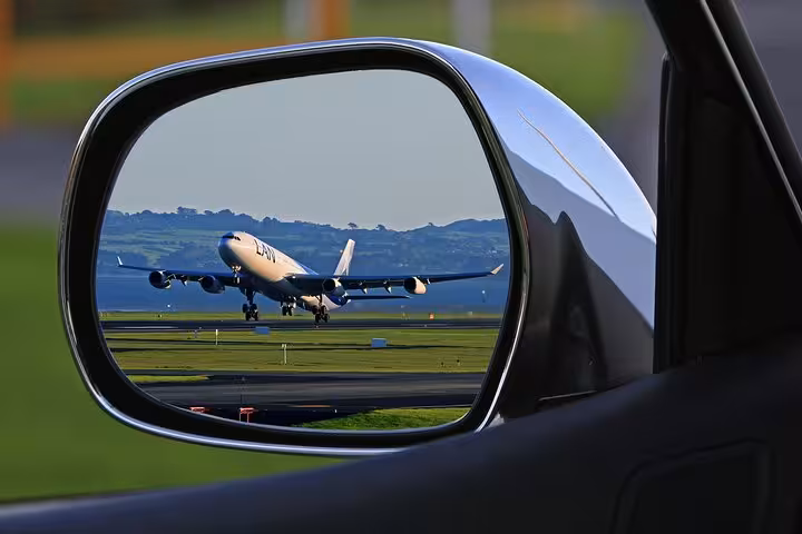 Airplane taking off from Bologna airport seen in car side mirror for Ravenna cruise transfer.
