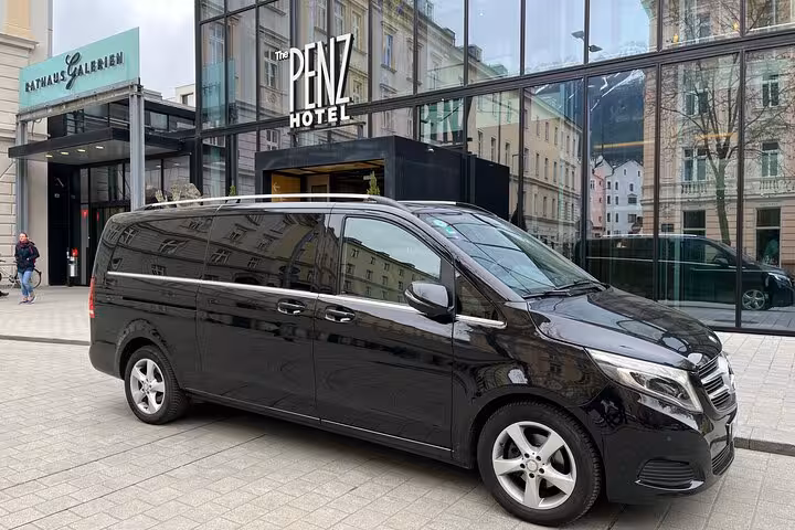 Elegant black van in front of a modern hotel, showcasing premium transfer service from Bologna to Ravenna port.