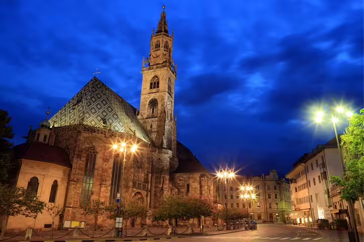 Bolzano Cathedral at dusk with lit piazza, key stop on Bolzano scavenger hunt self-guided highlights tour