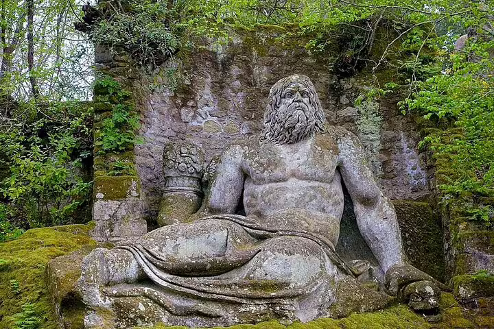 Ancient reclining giant stone god in lush Bomarzo Monster Park, visited on the Rome Calcata Bomarzo private tour
