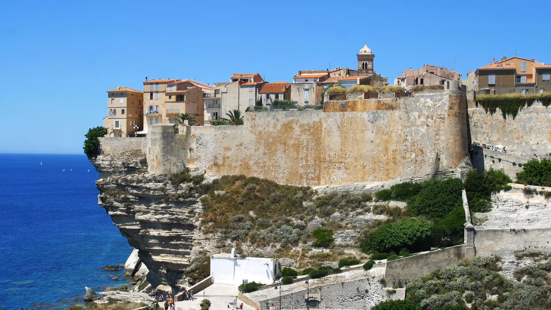 Stunning view of Bonifacio's cliffside architecture overlooking the turquoise Mediterranean Sea in Corsica.