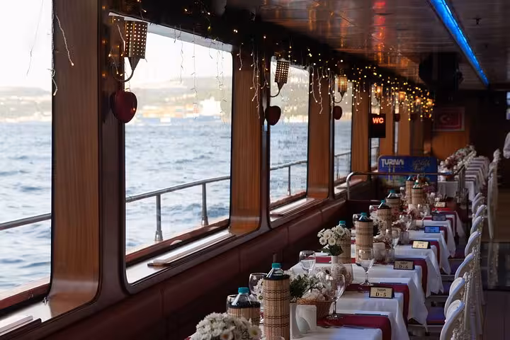Bosphorus dinner cruise dining cabin with window sea views, set tables and festive lights in Istanbul