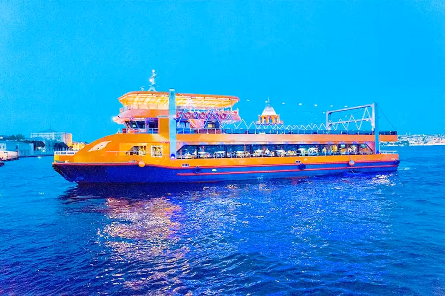 Illuminated cruise boat sailing the Bosphorus Strait at night, Istanbul dinner cruise with views and onboard dining