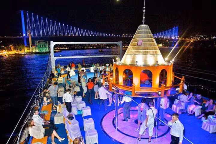 Bosphorus dinner cruise deck at night with Turkish Night show, lights and bridge views in Istanbul