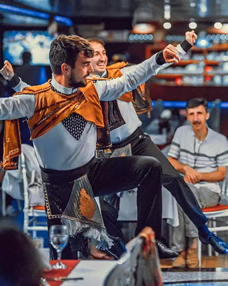 Traditional Turkish male dancers performing live show during Bosphorus dinner cruise in Istanbul at night