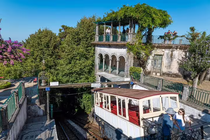 Tourists explore Braga's scenic funicular, surrounded by lush greenery and historic architecture on a sunny day.