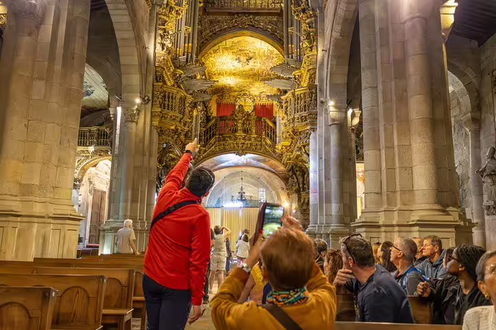 Tour group marvels at the ornate interior of a historic church in Braga, highlighting its golden decorations.