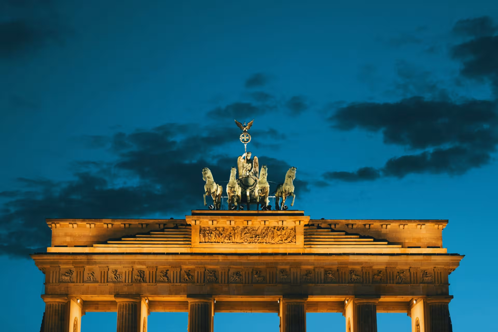 Brandenburg Gate illuminated at night against a dramatic sky, a must-see landmark on Berlin city tours.