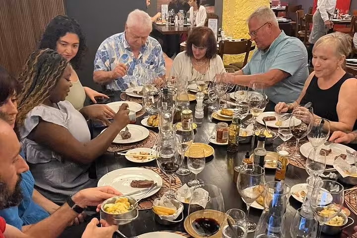 Group enjoying a lively Brazilian BBQ dinner experience with wine in a Rio restaurant setting.