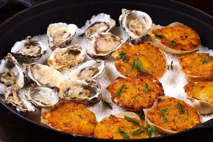 A selection of grilled oysters and Brazilian stuffed shells served on a bed of salt, showcasing Rio's culinary delights.