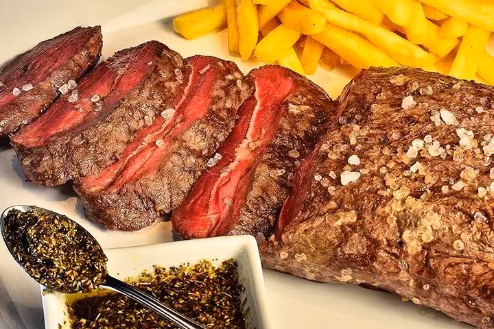 Juicy sliced steak with coarse salt served with golden fries and a side of Brazilian chimichurri sauce.