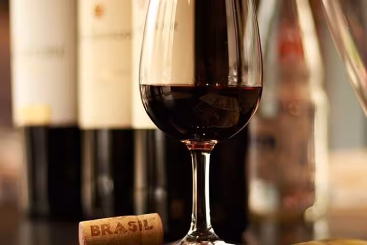 A glass of Brazilian red wine with bottles in the background, highlighting the wine offerings in a Rio dining experience.