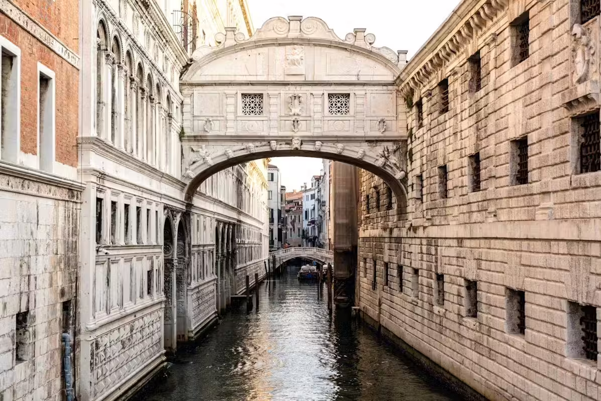 View of the Bridge of Sighs over a quiet Venice canal, a must-see stop on a private city highlights tour with bell tower access
