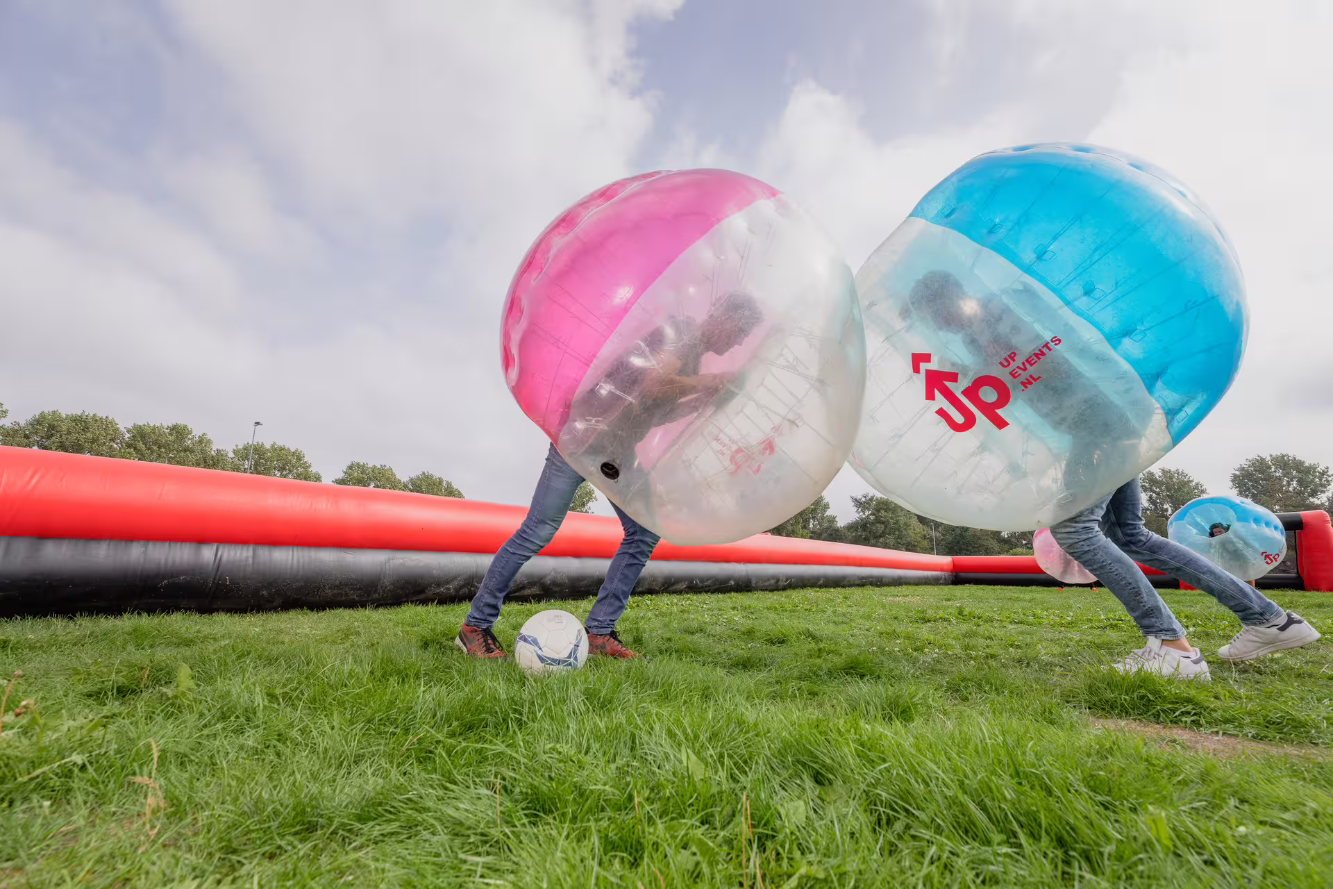 Players collide in giant bubble suits during bubble football in Amsterdam on an outdoor grass pitch