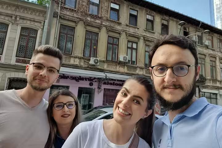 Four young adults smiling together on a Bucharest street with historic communist-era buildings in background