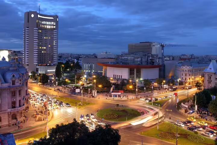 Bucharest city center at night with illuminated roundabout, historic buildings, and light trails from traffic