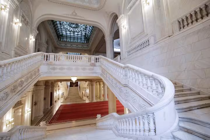 Majestic grand staircase inside Bucharest's Palace of Parliament, showcasing intricate architecture on Italian guided tour.