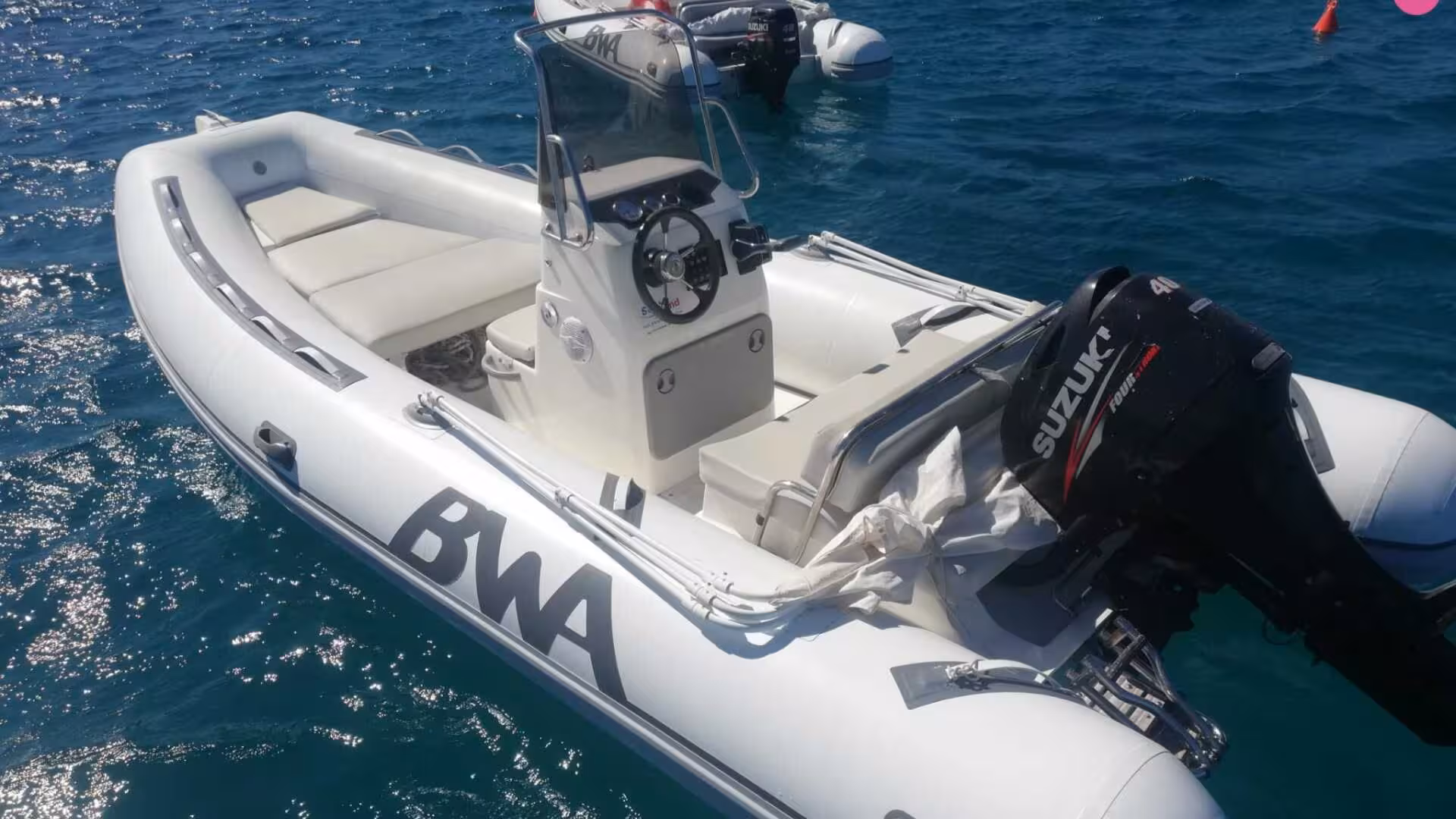 Sleek BWA RIB boat with Suzuki outboard motor floating on Calasetta's deep blue sea, perfect for exploration.