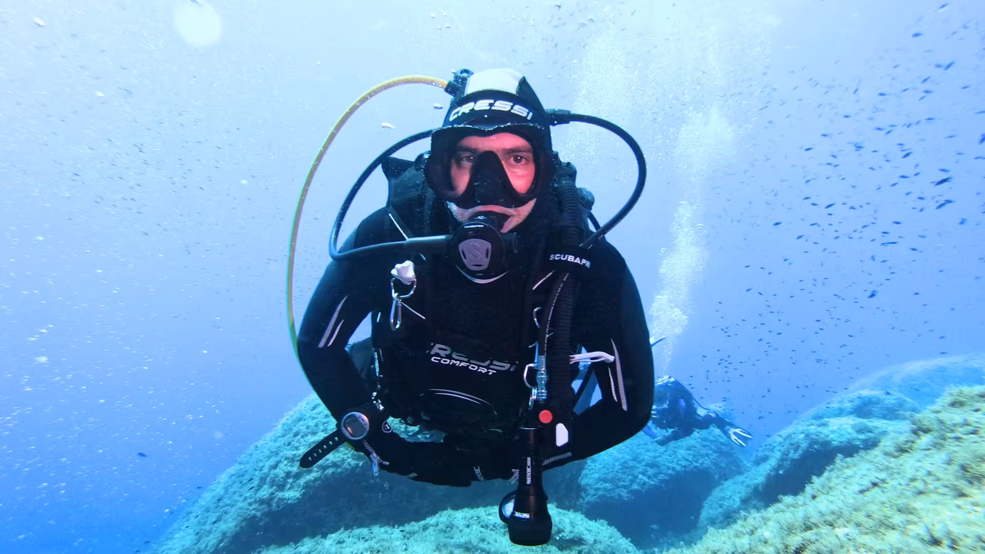 Diver in full gear enjoys a beginner scuba adventure in Cagliari's vibrant underwater world.