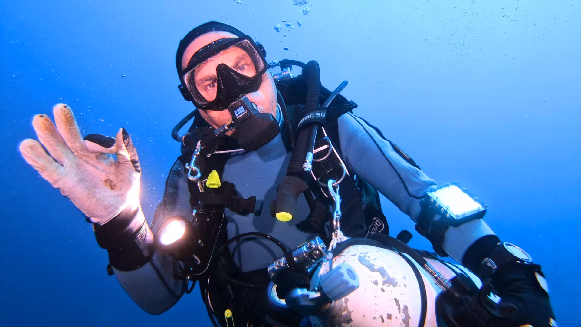 Diver giving an OK sign while exploring the vibrant marine life of Cagliari, ideal for beginner scuba diving tours.
