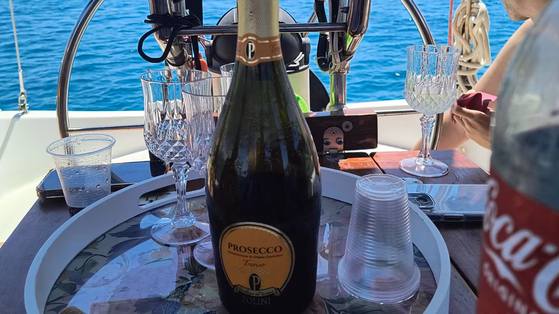 Close-up of a bottle of Prosecco and glasses on a sailboat in Cagliari, highlighting luxury sailing excursion amenities.