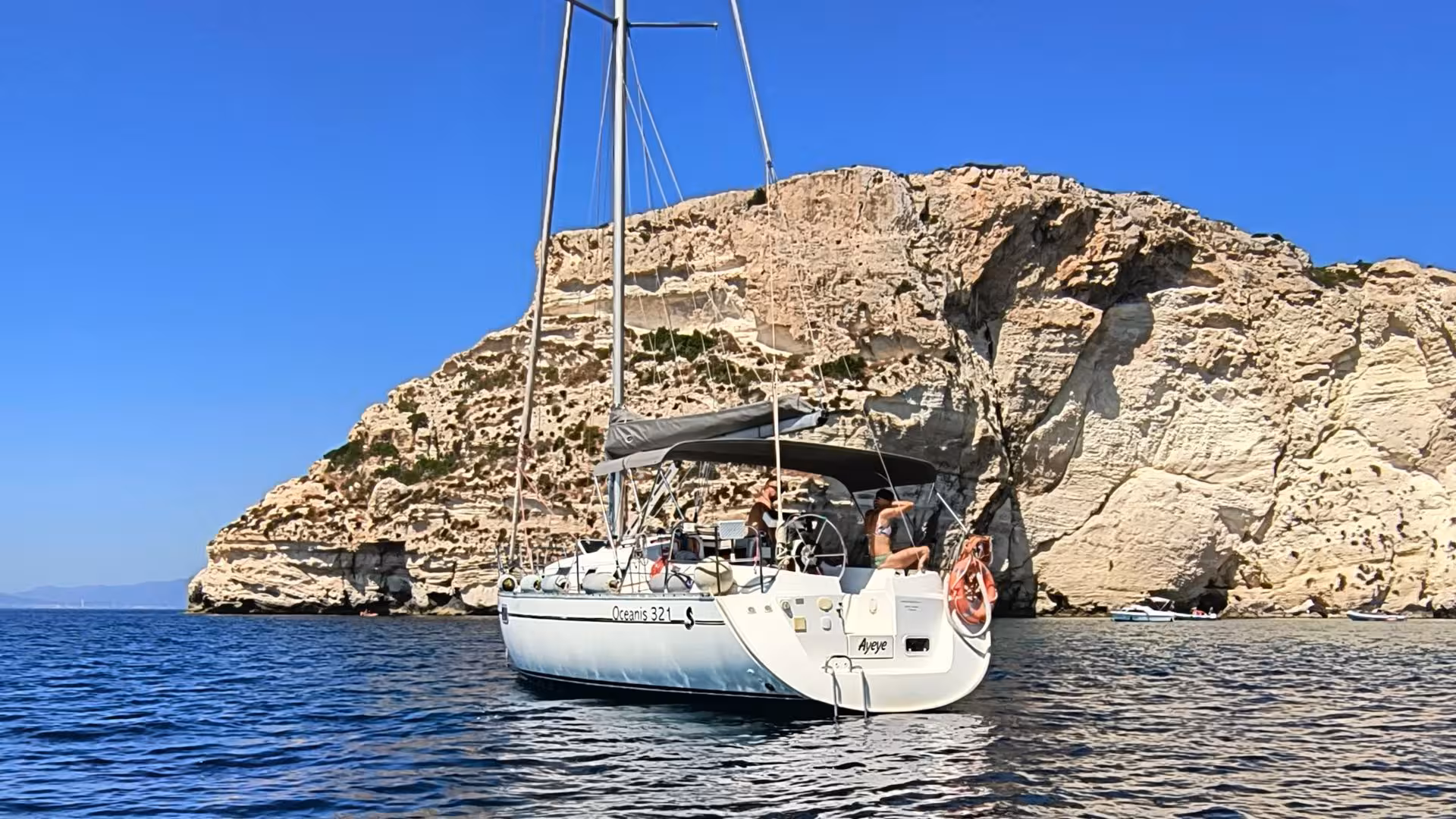 Sailboat anchored near stunning rocky cliffs in Cagliari, offering breathtaking views on a sailing excursion.