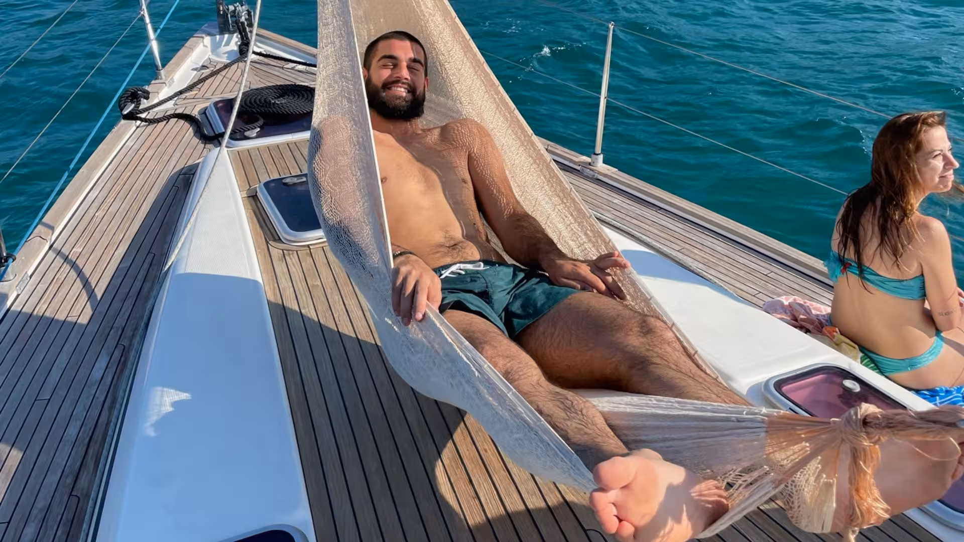 Relaxing on a hammock aboard a sailing boat on the Cagliari tour to Mari Pintau, enjoying the sun and sea breeze.
