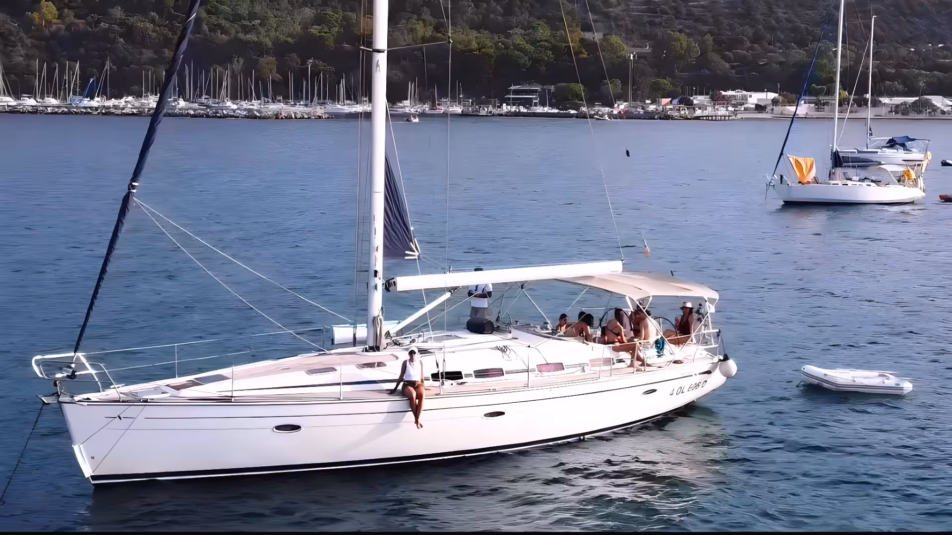 Sailing boat with passengers enjoying a sunny day on calm waters, docked near the scenic coast of Cagliari.