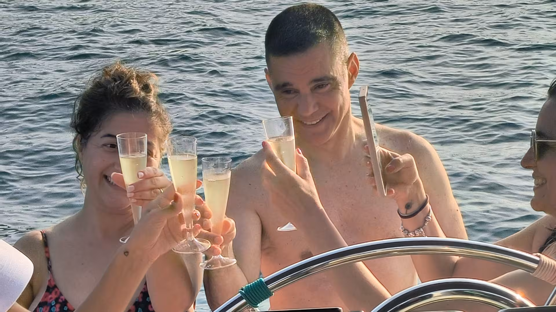 Group enjoying champagne toasts on a sunny Cagliari sailing excursion, creating unforgettable memories at sea.