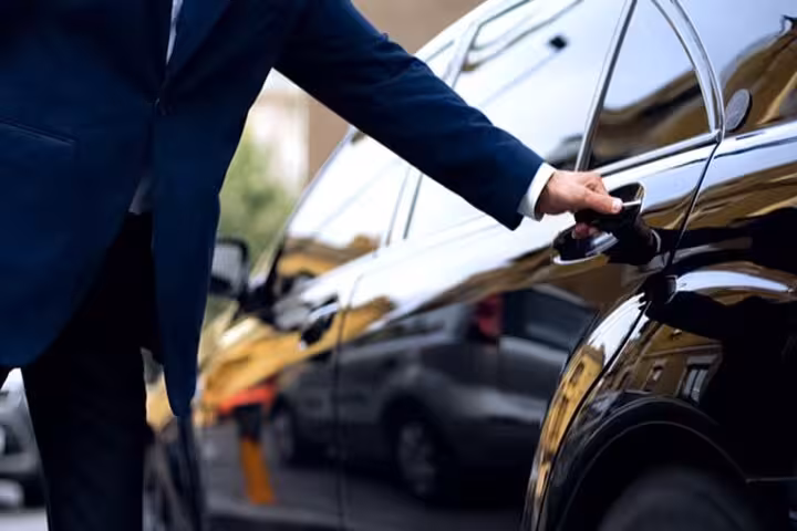 Professional driver opening black sedan door for private Cairo hotel to airport transfer service