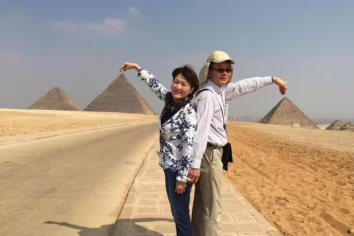 Visitors posing on the desert road with the Pyramids of Giza on a Cairo day tour to the Egyptian Museum and bazaar