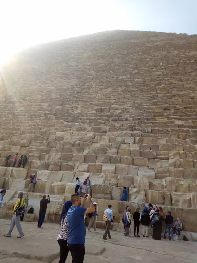 Tourists at the base of the Great Pyramid of Giza on a Cairo day trip with flights from Sharm El Sheikh