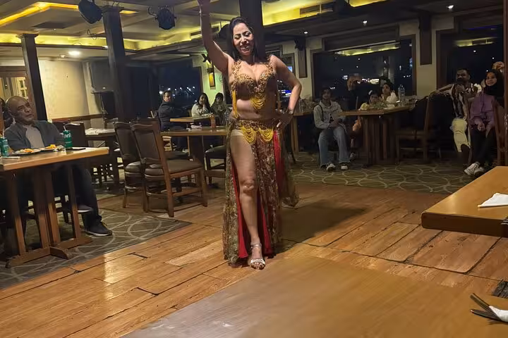 Belly dancer performs on Cairo Nile dinner cruise with seated guests, live entertainment and hotel pickup