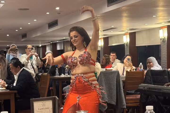 Belly dancer performing live on Cairo Nile dinner cruise with seated guests and onboard dining ambiance