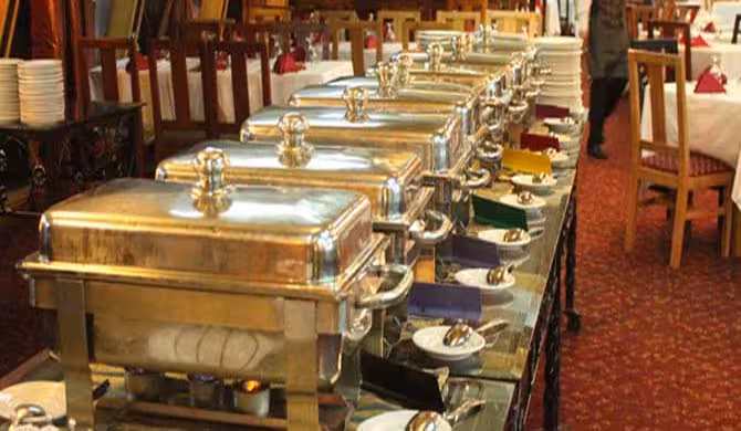 Buffet dinner setup on Nile cruise in Cairo with hot chafing dishes, plates and dining tables onboard