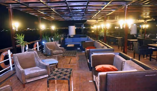 Open-air lounge deck seating on Cairo Nile River dinner cruise boat with evening lights and views