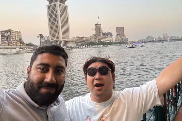Guests on Cairo Nile dinner cruise selfie with river skyline at sunset, hotel pickup evening tour